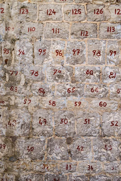 Stone wall with numbered stones. Two-digit red numbers on the stones. Restoration of the wall. — Stock Photo, Image