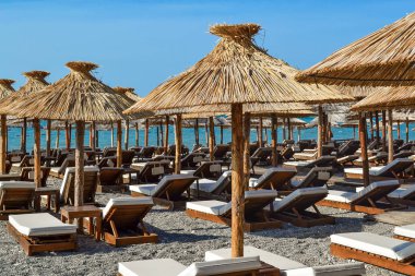 Yumuşak şezlonglar ve güneş plaj ile hasır şemsiyeler. Adriyatik kıyısı. Yaz. İnsanlar.