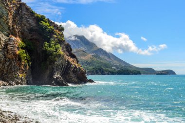 Güzel oda. Dağların denize inerler. Mavi gökyüzü bulutlar ve turkuaz su ile. Adriyatik Denizi. Karadağ.