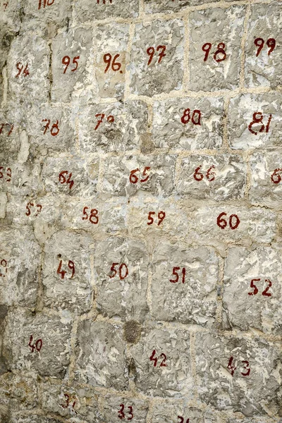 Stone wall with numbered stones. Two-digit red numbers on the stones. Restoration of the wall.