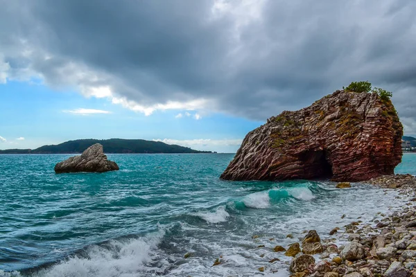 Las olas se rompen contra la costa pedregosa. El cielo está cubierto de nubes bajas. Islas de piedra. Montenegro — Foto de Stock