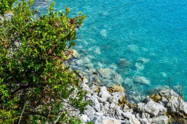 Dağdan deniz manzarası. Adriyatik Denizi. Kayalık kıyı. Suyun altında denize düşen büyük taşlar görülüyor.