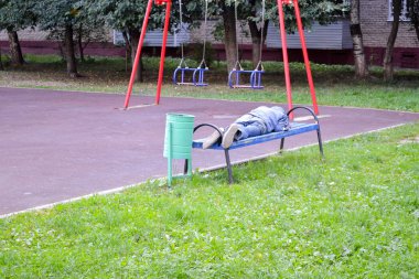 Evsiz adam oyun alanında bir bankta uyuyor. Rusya. Moskova bölgesi