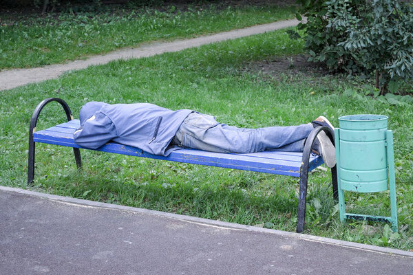 The homeless man sleeps on a bench in the playground. Russia. Moscow region