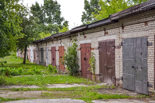 Uma fila de garagens de tijolos com portões de metal enferrujado. Rússia — Fotografia de Stock