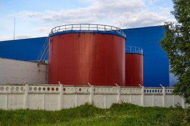 Mavi endüstriyel binaya karşı kırmızı renkli büyük endüstriyel tanklar