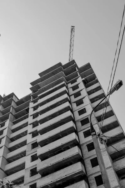 Construction in progress. Residential multi-storey building. House and crane. Monochrome image