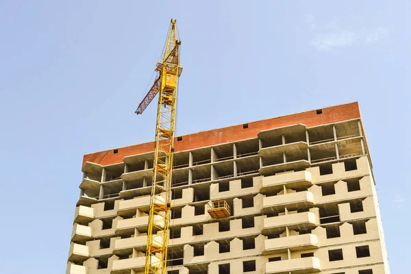 Строительный кран на фоне строящегося многоэтажного здания — стоковое фото