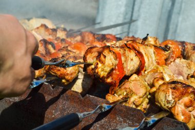 Izgara kebap pişirme metal şiş closeup. Barbeküde pişirilen kavrulmuş et. Geleneksel doğu yemeği, şiş kebap. Kömür ve alev üzerinde Izgara, piknik
