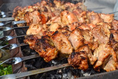 Izgara kebap pişirme metal şiş closeup. Barbeküde pişirilen kavrulmuş et. Geleneksel doğu yemeği, şiş kebap. Kömür ve alev üzerinde Izgara, piknik