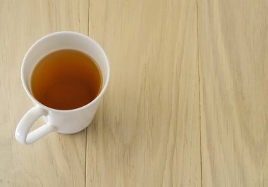 Tahta bir masada beyaz bir fincan çay. Sağ taraftaki yazı için yer