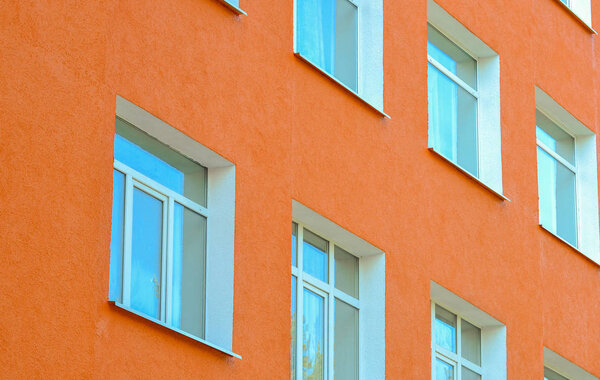 Facade building with pink walls and rows of plastic windows