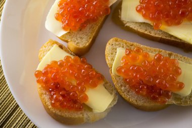 Ekmek ve tereyağı nda kırmızı havyar, beyaz tabakta dört sandviç. Yukarıdan görüntüle