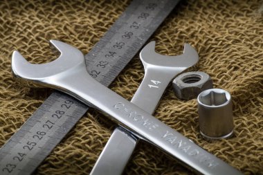 Anahtarlar ve metal cetvel pürüzlü bir kumaşa yakın. Kahverengi arka plan. Yan görünüm.