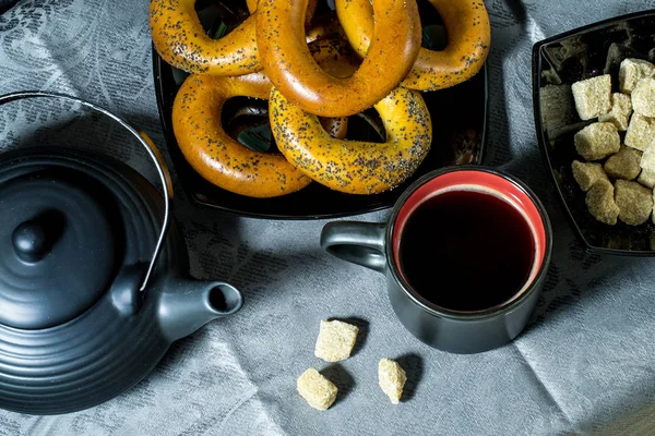 Bagels, tasse à café, théière et sucre en noir sur une nappe bleue. Vue d'en haut — Photo