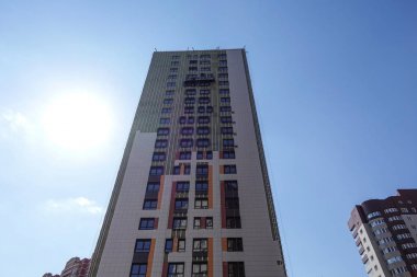 2019 Nisan 19, Moskova, Rusya Yüksek katlı bina mavi gökyüzüne karşı yapım aşamasında. Bina dış dekoratif paneller ile kesilmiş. Rusya