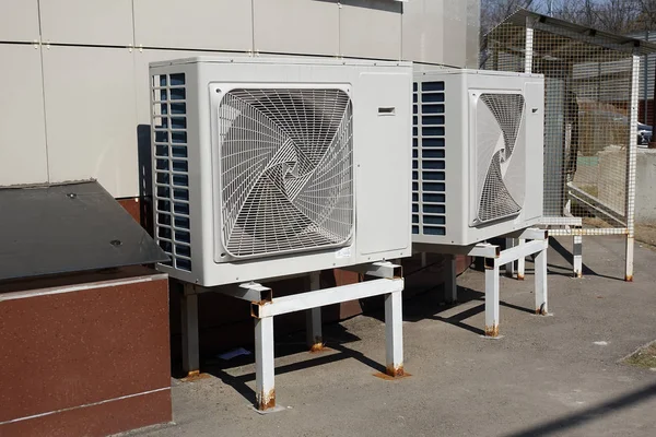Condensadores de ar condicionado industriais (unidade externa) no chão perto do edifício em um dia quente de verão — Fotografia de Stock