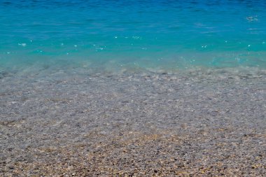 Sakin deniz ya da okyanus. Mavi veya masmavi su rengi. Berrak ve mavi gökyüzü. Güneşli yaz havası. Plaj, seyir, tropik ada.