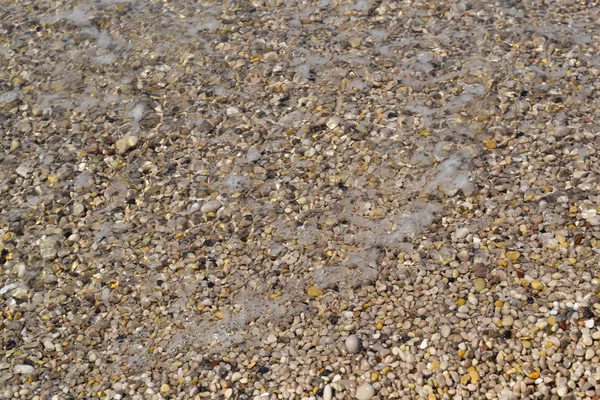 Sea foamy wave on a pebble beach top view — Stock Photo, Image