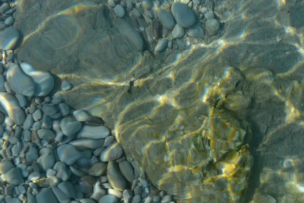 Meeressteine im Meerwasser. Kiesel unter Wasser. Der Blick von oben. Nautischer Hintergrund. Sauberes Meerwasser. Transparentes Meer. — Stockfoto