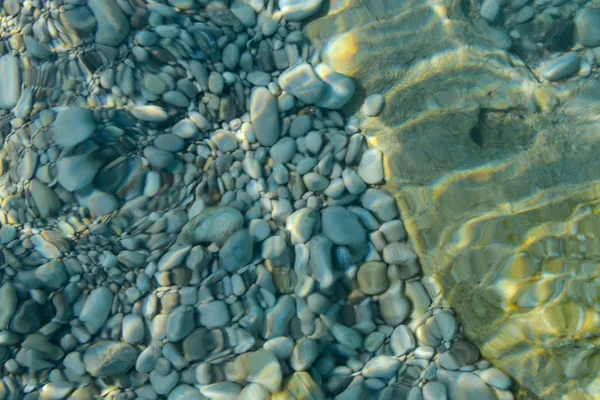 Meeressteine im Meerwasser. Kiesel unter Wasser. Der Blick von oben. Nautischer Hintergrund. Sauberes Meerwasser. Transparentes Meer. — Stockfoto