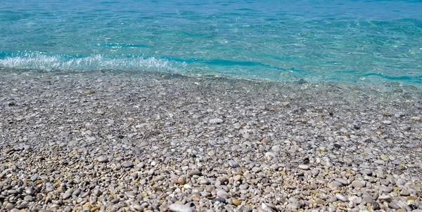 Θαλάσσιο υπόβαθρο. Η ακτή με τα βότσαλα. Μικρά κύματα τρέχουν στην ακτή — Φωτογραφία Αρχείου