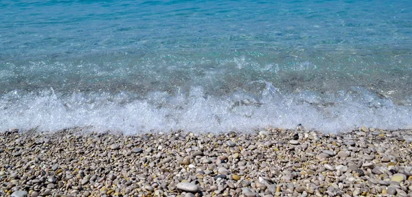 Fondo marino. La costa de guijarros. Pequeñas olas corren por la costa — Foto de Stock