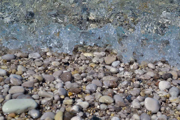Deniz arka planı. Çakıl taşları sahili. Küçük dalgalar sahilde koşar. — Stok fotoğraf