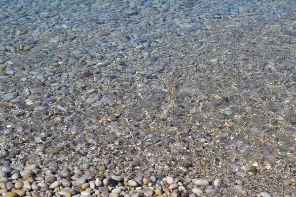 Το θαλάσσιο κύμα μετακινείται σε μια παραλία με βότσαλα. Καλοκαιρινή ηλιόλουστη μέρα. Θέα από πάνω — Φωτογραφία Αρχείου