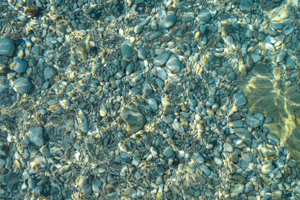 Draufsicht auf blaue, grüne und türkisfarbene Wasserfarben, Meeresoberfläche auf Felsen und Boden. Reflexion der Sonnenstrahlen im Wasser, flacher Boden, Untiefen des Ozeans. Meeresstruktur, Hintergrund, Muster, Tapete. — Stockfoto