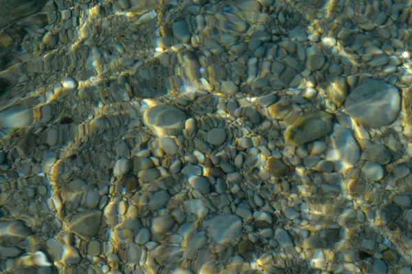 Vista superior de los colores azul, verde y turquesa del agua, superficie del mar en las rocas y el fondo. Reflejo de rayos de sol en el agua, suelo poco profundo, cardumen del océano. Textura del mar, fondo, patrón, fondo de pantalla . — Foto de Stock