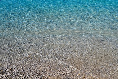 Açık deniz suyu dokusu, kayalık zeminin üst görüntüsü. Şeffaf tropikal okyanus, mercan resifleri, soyut zümrüt su yüzeyi arka planı