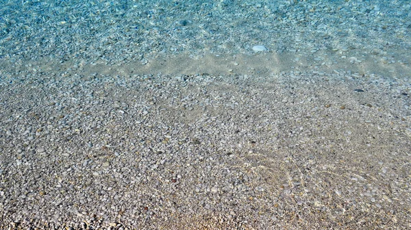 Czysta woda morska tekstura, widok z góry na skaliste dno. Przezroczysty ocean tropikalny, rafy koralowe, abstrakcyjne szmaragdowe tło powierzchni wody — Zdjęcie stockowe