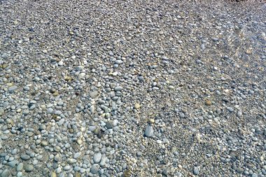 Deniz dalgası çakıl bir plaja taşınır. Yaz güneşli bir gün. Yukarıdan görüntüle