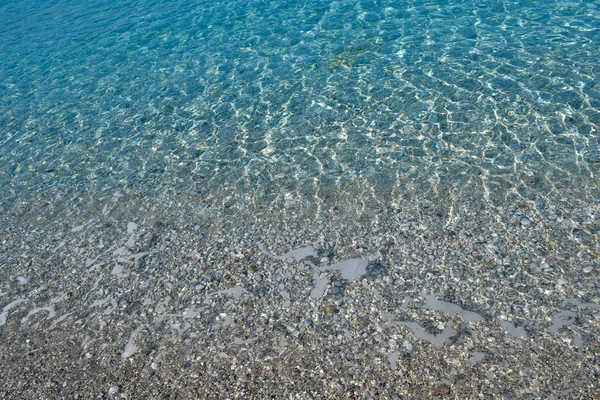 Όμορφα πολύχρωμα βότσαλα και μεγάλη πέτρα κάτω από γαλαζοπράσινα καταγάλανα νερά, γραφικό θαλάσσιο φόντο ή υφή, κορυφή θέα — Φωτογραφία Αρχείου
