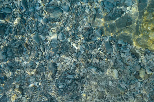 Schöne bunte Kieselsteine und großer Stein unter türkisblauem, klarem Wasser, malerischer mariner Hintergrund oder Textur, Draufsicht — Stockfoto