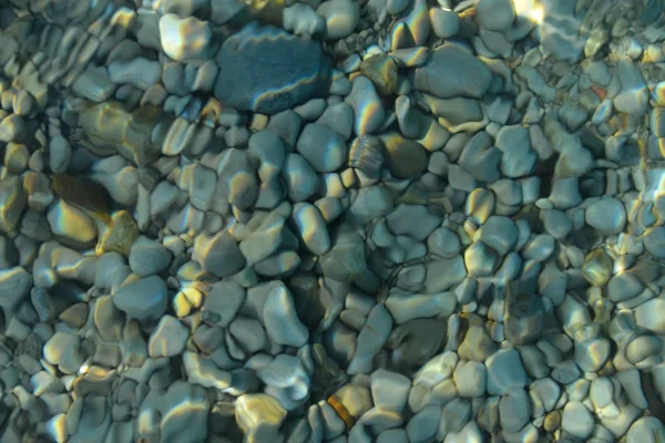 Schöne bunte Kieselsteine und großer Stein unter türkisblauem, klarem Wasser, malerischer mariner Hintergrund oder Textur, Draufsicht — Stockfoto
