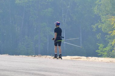 Bir atlet roller patenciler üzerinde eğitim. Biatlon rulo kayak kayak Polonyalılar, kask ile binmek. Sonbahar egzersiz. Silindir spor. Yetişkin kişini paten.