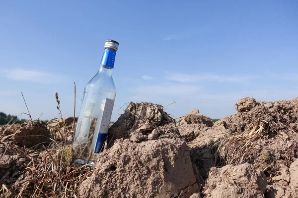 Image of an empty bottle of vodka on the background of a plowed field. Russia — Stock Photo, Image