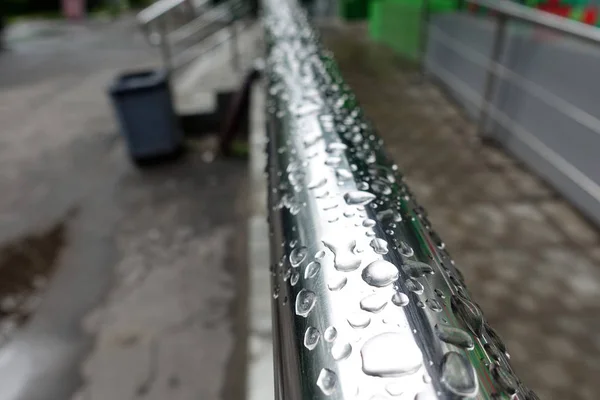 Water drops on metal railing during heavy rain