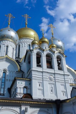 Parlak mavi gökyüzünün arka planında ortodoks tapınağı haçları olan altın kubbeler. Kar beyazı görünümü. Hıristiyan inancı.