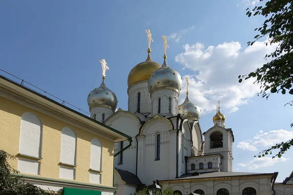 Cúpulas doradas con cruces de un templo ortodoxo en el fondo del cielo azul brillante. Fachada blanca como la nieve. Fe cristiana. —  Fotos de Stock