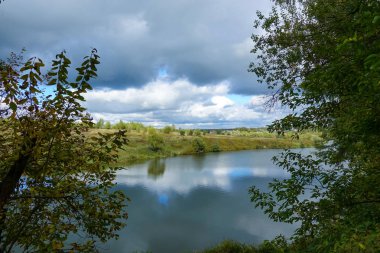 Gökyüzünde güzel yağmur bulutları, nehrin üzerinde ve sonbaharda bozkır..