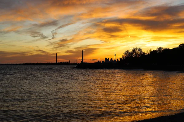 Sunset in city Toronto. Darkness cityscape. Blue and yellow colors cloudy sky and lake Ontario