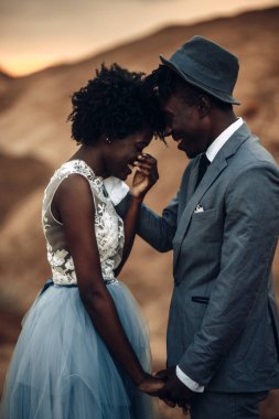 Siyah mutlu yeni evliler el ele, neşeli gülmek ve güzel manzara karşı durmak. Portre.