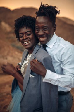 Siyah damat gelini günbatımında Kanyon güzel manzara karşı ceketi giymiş sarılmak. Neşeli gülüyorlar. Portre.