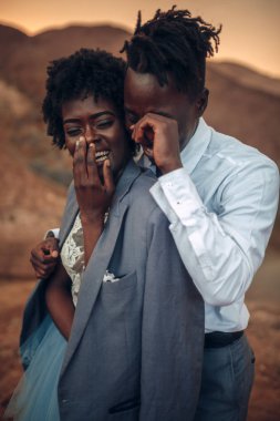 Siyah damat gelini günbatımında Kanyon güzel manzara karşı ceketi giymiş sarılmak. Neşeli gülüyorlar. Portre.