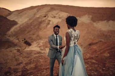 Siyah mutlu yeni evliler Kanyon güzel manzara karşı günbatımında yürümek. Gelini üzerinde odaklanmıştır.