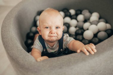 Gözü yaşlı bebek sepeti küçük toplar ve çığlıkları ile duruyor. Üstten görünüm.
