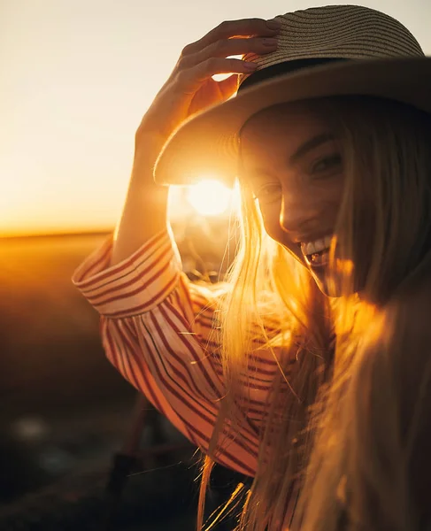 帽子とシャツの若い女性は 夕日を背景のに対して元気よく笑っています バックライト — ストック写真